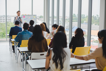 Asian male speaker is speaking at seminars and workshops to the people in the meeting.