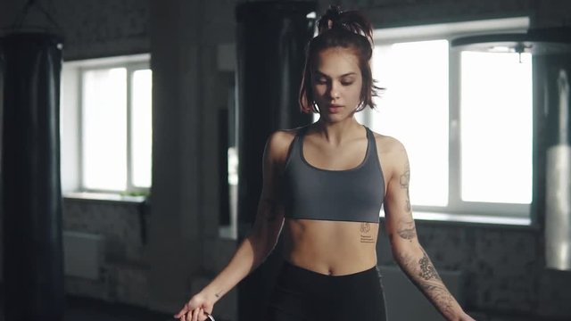 athletic girl jumping rope. athlete in sportswear trains in the gym. slow motion