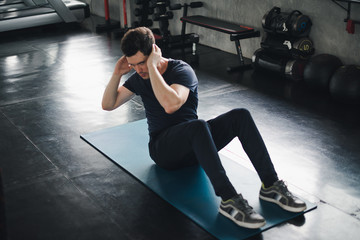 Young man caucasian Being exercised by a sit-up on yoga mat. He wears sportswear. Fitness in the gym concept.