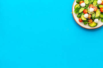 Healthy lunch. Fresh vegetable salad on blue background top view copy space
