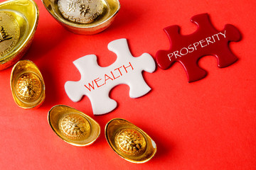 Gold ingots and white puzzle for Chinese New Year festive decorations on a red background. Chinese...