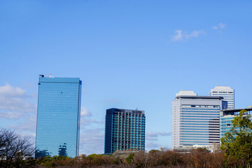 Scenery view of glass and office building on blue sky background. Office glass building is generally popular because it's helping to lights and reduce energy of air conditioner in the building.