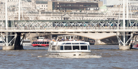 London, United Kingdom - Februari 21, 2019: A City cruises touristic boat navigating by Thames river with a lot of tourists on it, in London, UK