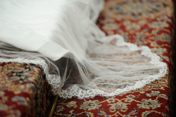 Velo de vestido de novia sobre alfombra roja con motivos florales