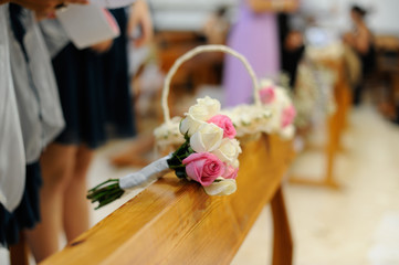 Ramo de novia con flores rosas y blanca sobre banco de iglesia en ceremonia de boda