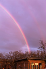 Bright multi-colored rainbow in the rays of the evening sunset sun against the sky in clouds after rain. Rainbow, Good News, Gospel