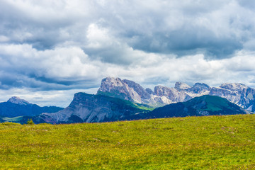 Fototapeta premium Alpe di Siusi, Seiser Alm with Sassolungo Langkofel Dolomite, a large green field with a mountain in the background
