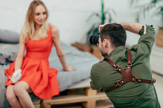 young photograther working with a client, close up photo, attractive madel in oranger dress in the blurred background