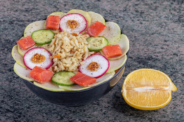 Poke bowl trand. Raw fish, rice and halhy vegetables on wooden background.