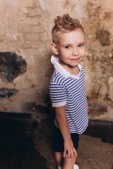 Fashionable cute adorable caucasian boy model posing on art loft style background. Fashion kids, childhood, beauty concept