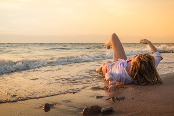 Girl rests and has fun in sea wave at sunset