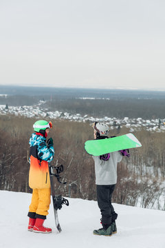 two ambitious snowboarders sharing with experiense outdoors, full length photo. side view