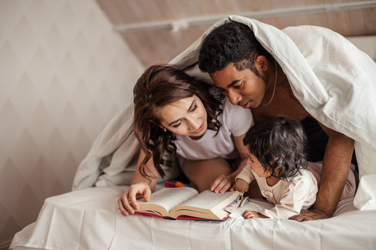 young family reading interesting magic story under the blanket. close up photo, free time, spaare time