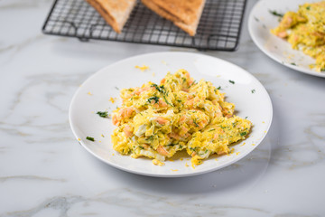 Räucherlachs Rührei mit Dill und Vollkorn Toast auf Marmor Hintergrund