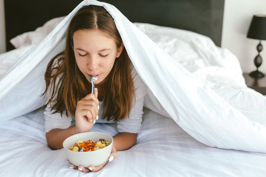 Portrait Of A 12-13-14 Years Old Teenage Girl Eating Healthy Meal In Bed