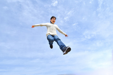 Naklejka na ściany i meble Japanese girl jumping in the blue sky