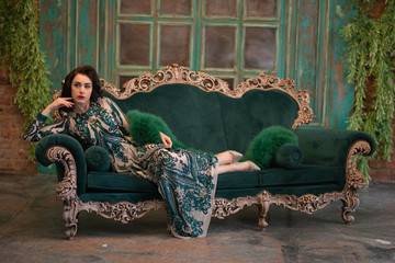 elegant caucasian girl in a luxurious long sequins lace dress with a green fluffy boa in her hands...