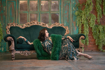 elegant caucasian girl in a luxurious long sequins lace dress with a green fluffy boa in her hands...