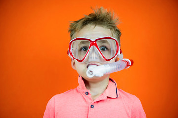 funny boy in swimming goggles and snorkel on bright orange background