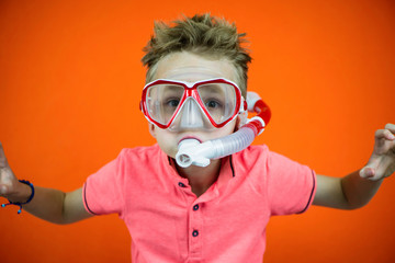 funny boy in swimming goggles and snorkel on bright orange background