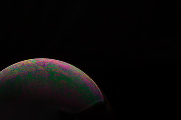 A bubble in rainbow colors on a black background.