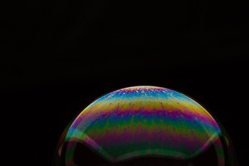 A bubble in rainbow colors on a black background.