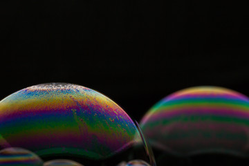 A bubble in rainbow colors on a black background.