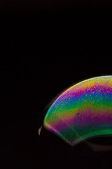 A bubble in rainbow colors on a black background.