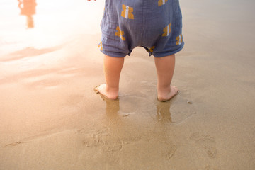 Little  baby's legs staning on the beach in the holiday time