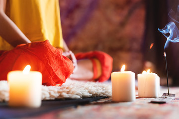 Close-up of woman's hand in yoga lotus pose meditating in a crafting room with candles