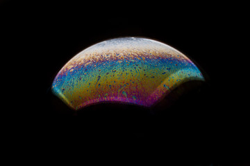 A bubble in rainbow colors on a black background.
