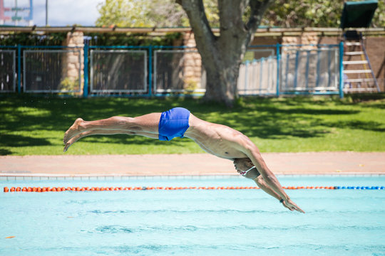 Close up image of a swimmer diving into a swimming pool during training for a big swimming race