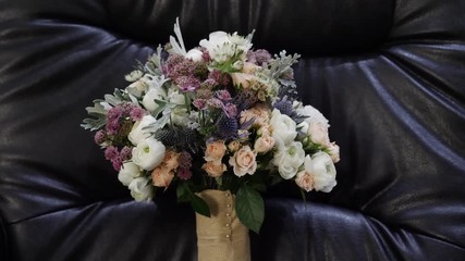 Wedding bouquet on a black leather sofa