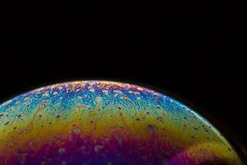 A bubble in rainbow colors on a black background.