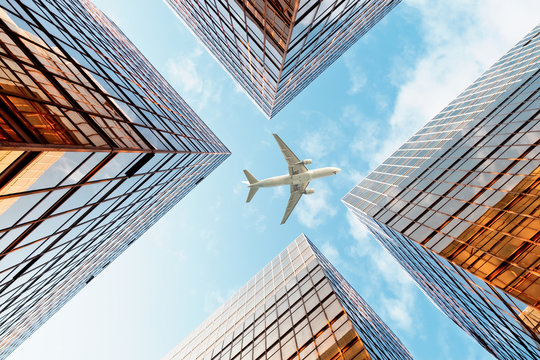 Airplane flying over business skyscrapers