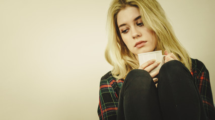 Fototapeta premium Sad lonely woman sitting on couch with mug