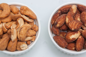 salted Cashews and almonds snack put on white background, Isolate dry and salted cashews and almonds in small white cup