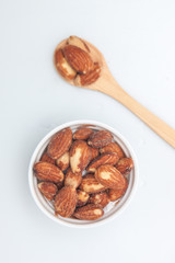Almonds in the white small cup and wood spoon on white background, Isolate snack 