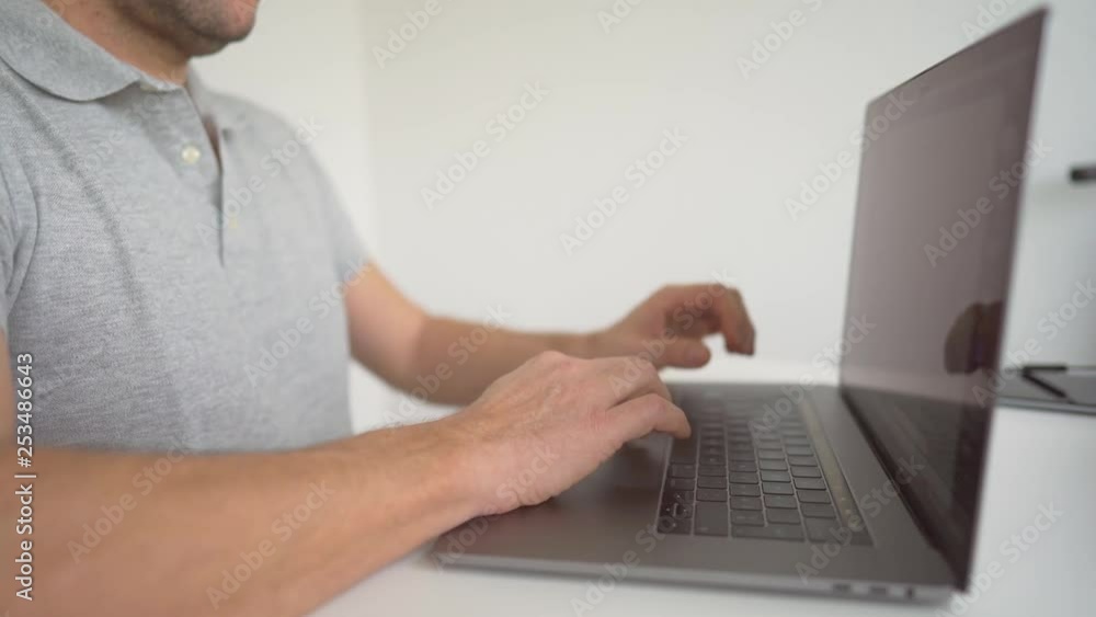 Poster a man sitting at the desk rapidly typing and working on a project on his laptop. staying focused on 