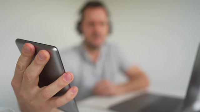 A man taking a brief break from working and listening to his favorite music, singing along with it.