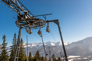 The mechanism of the ski lift, visible large, driving wheel pulling the rope and suspended chairs...