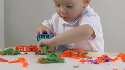 A two years old preschool child playing with modeling clay (compound). Smiling and looking at the camera. Early childhood education to children concept