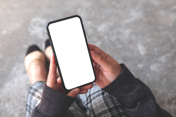 mockup image of a woman holding black mobile phone with blank desktop screen while sitting on the floor
