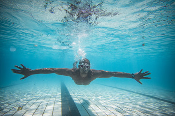 Underwater image of a male swimmer diving and swimming in a swimming pool to train