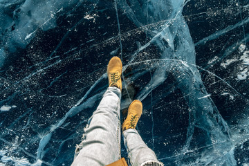 Men's yellow shoes on the pure blue ice of lake Baikal. Concept tourism and travel to famous places...