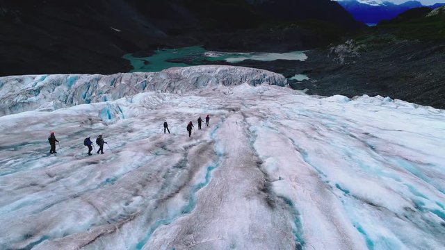 Fly over of a hike with a view of the mouth of a blue iced Alaskan glacier.