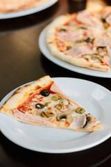 Mushroom pizza slice on white ceramic plate over the table.