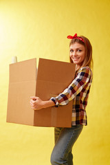 People moving new place and repair concept - Young woman holding cardboard box. Yellow background.