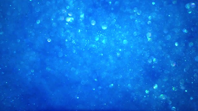 Abstract bright blue sparkly particle background with bokeh lights and shiny frozen crystals in water LOOP.