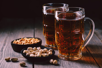 two mugs of lager beer and snacks set. bar table. restaurant, pub, food concept. delicious drink and salty nuts. oktoberfest atmosphere, craft brewery background